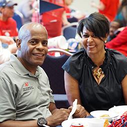 Two alumni members sitting at tailgate table.